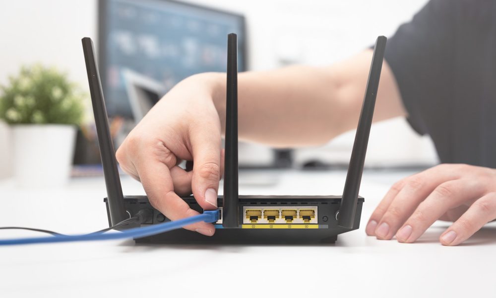 Man connects the internet cable to the router's socket. Fast and wireless internet concept